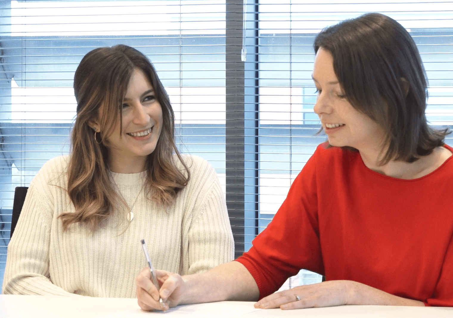 Two women collaborating over a sheet of paper