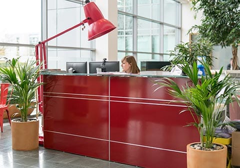 A receptionist behind a red desk