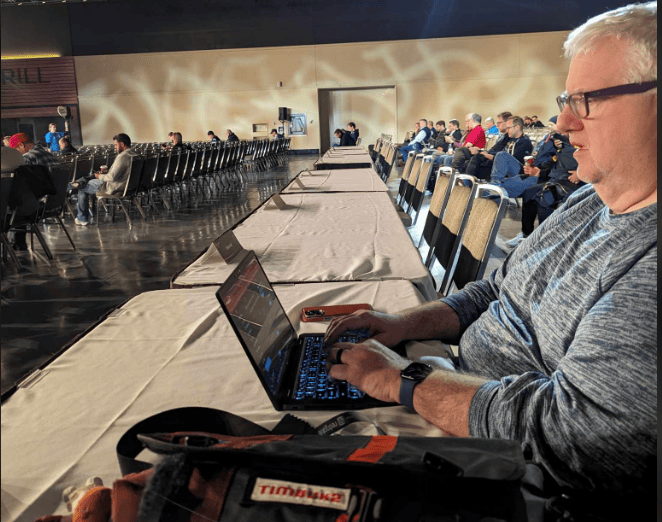 A person sitting at a table with a computer

Description automatically generated