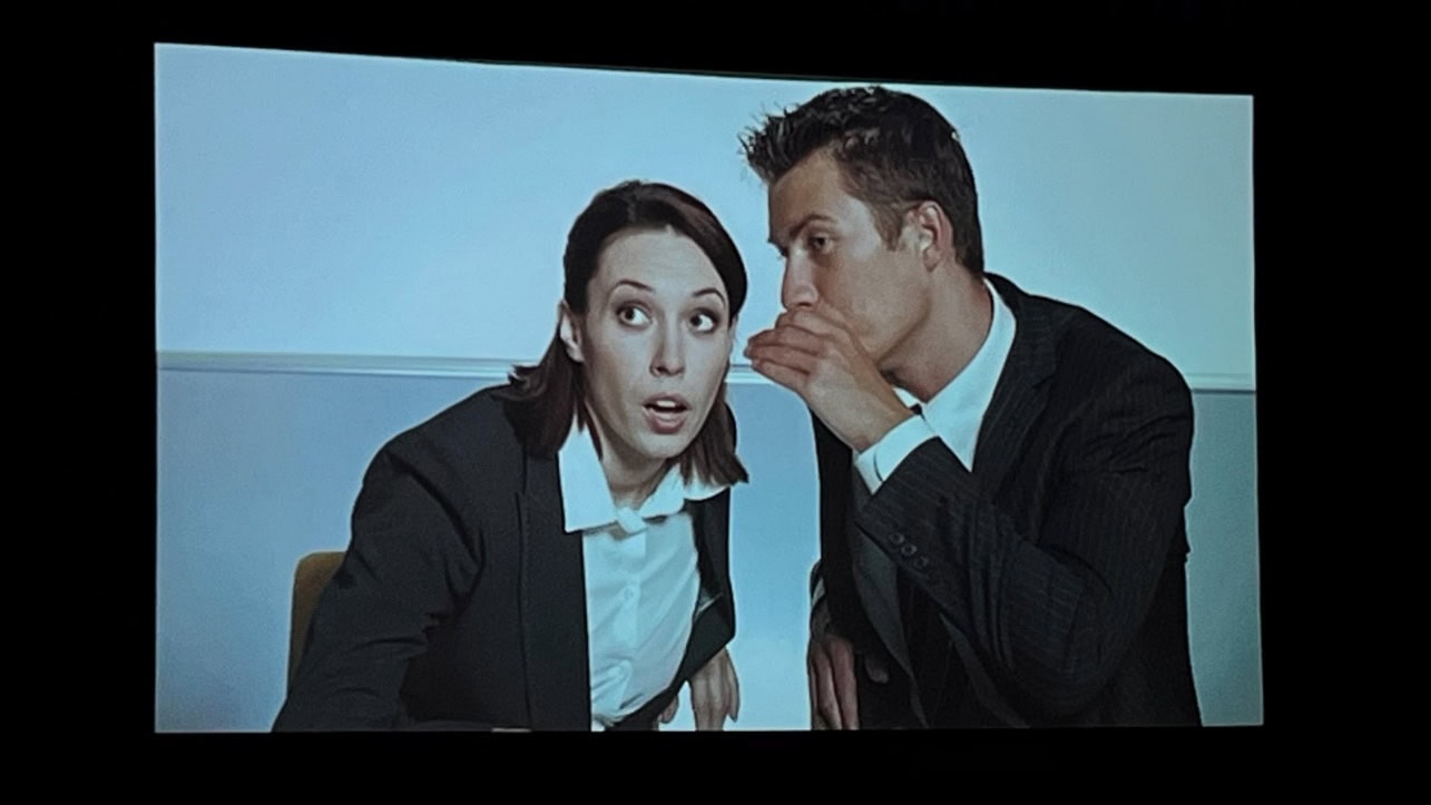 A person whispering into a person's ear

Description automatically generated