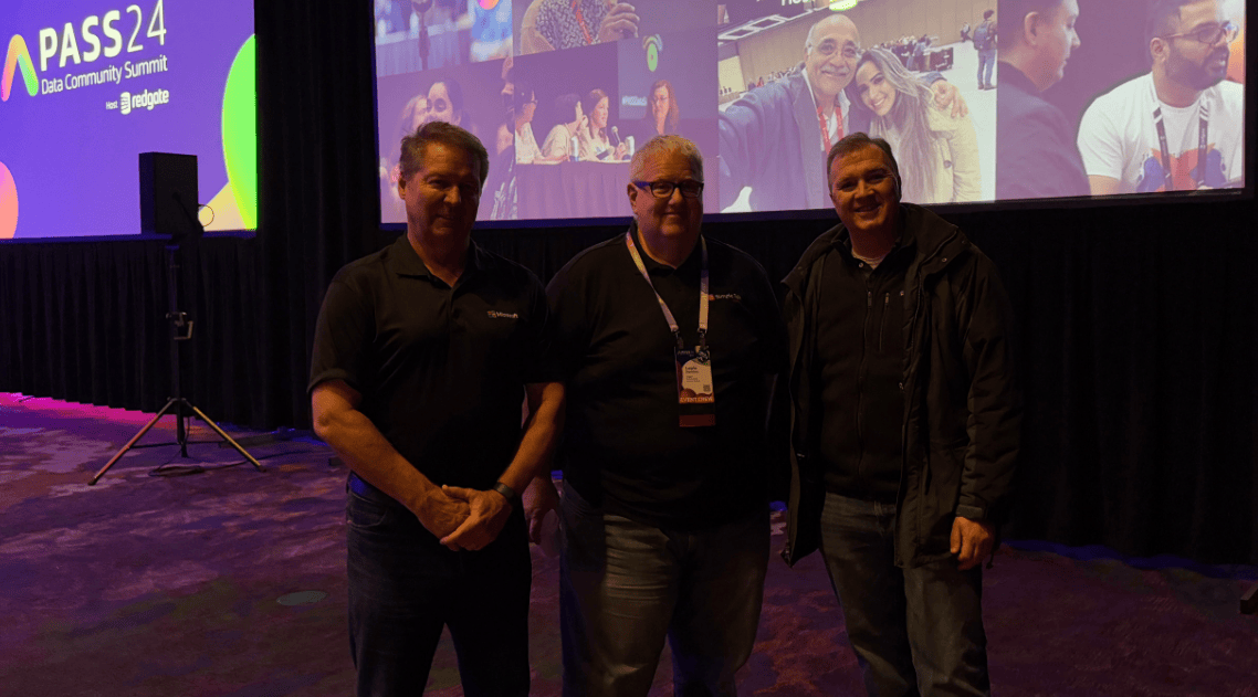 A group of men standing in front of a large screen
Description automatically generated