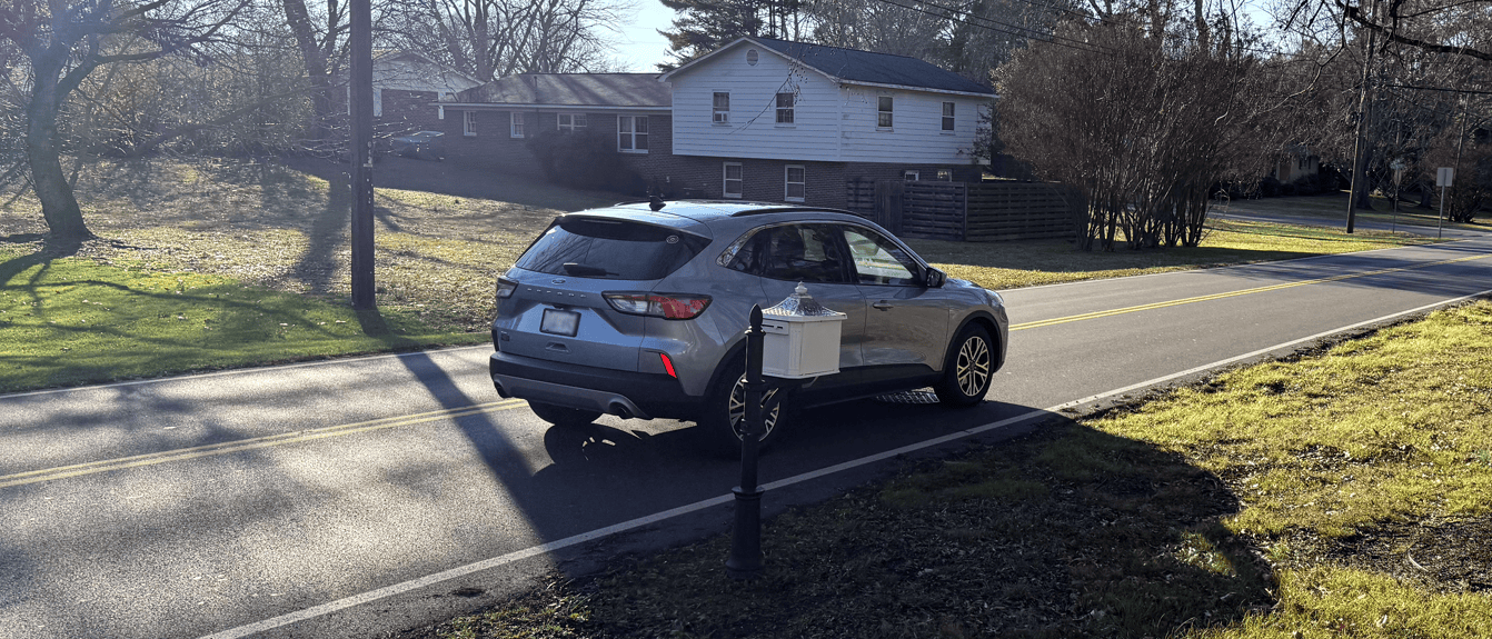 A silver car parked on the side of a road Description automatically generated